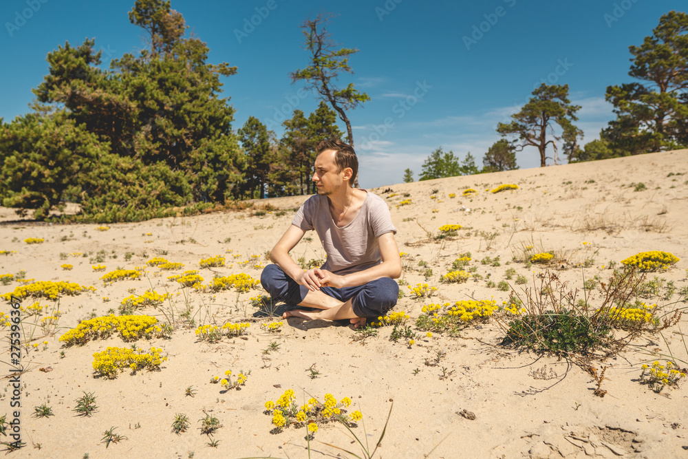 Man traveler relaxing on the beach of Olkhon island overlooking the water of the lake and the mountains and the blue sky