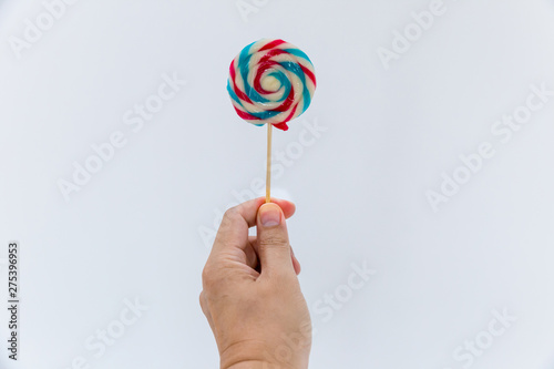 Fun and celebration concept.hand holding big colorful lollipop candy on stick, isolated on white background minimalism style.