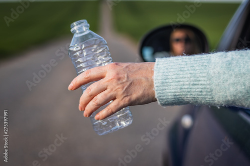 Do not pollute environment with plastic ! Driver hand holding plastic bottle from car window 