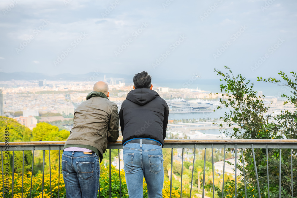 People looking at the Barcelona port from Montjuic castle. Harbour with ships in the city. Tourists enjoying the view.