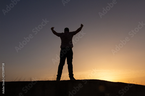 silhouette of man raising arms sunset © robcartorres