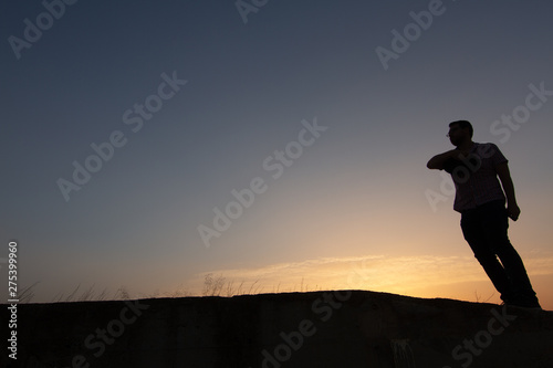 silhouette of man throwing hat at sunset