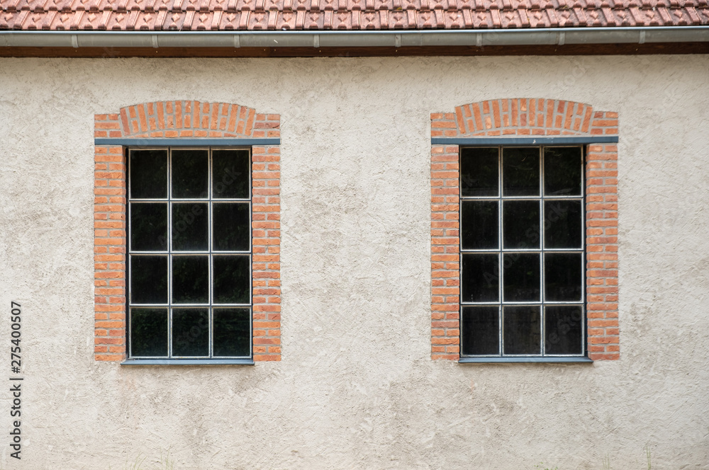 Two windows on a grey plaster wall