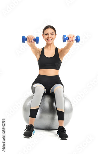 Young sporty woman doing exercises with fitball on white background