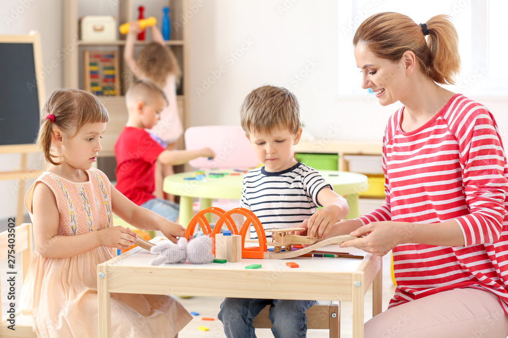 Nursery teacher with cute little children in kindergarten - obrazy, fototapety, plakaty 