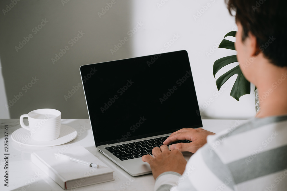 Businessman using laptop with tablet and pen on wooden table in coffee shop with a cup of coffee Businessman using laptop with tablet and pen on wooden table in coffee shop with a cup of coffee