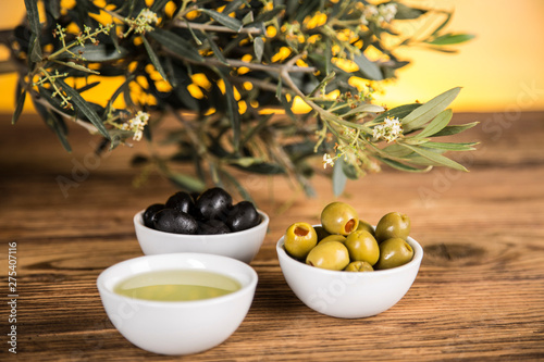 Olive oil, olive tree and green and black olives on a wooden table