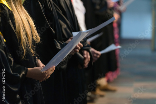 Fotografia Choir singers holding musical score and singing on student gradu