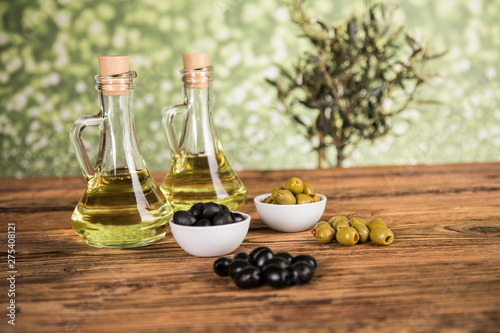 Olive oil, olive tree and green and black olives on a wooden table