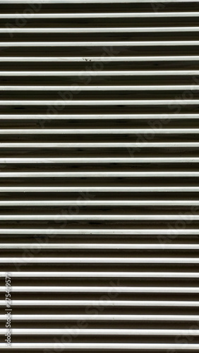 Antigua persiana metálica de lineas horizontales con gotas de pintura