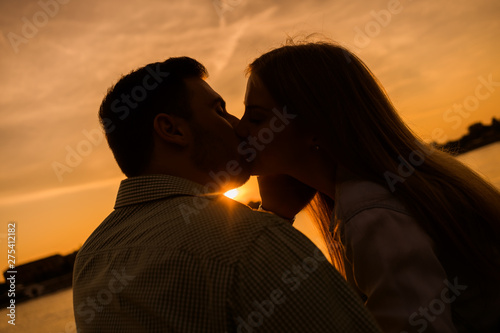 Happy couple is kissing in sunset in the city.