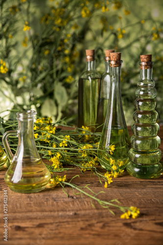 Rapeseed flowers and rapeseed oil in a bottle on the table