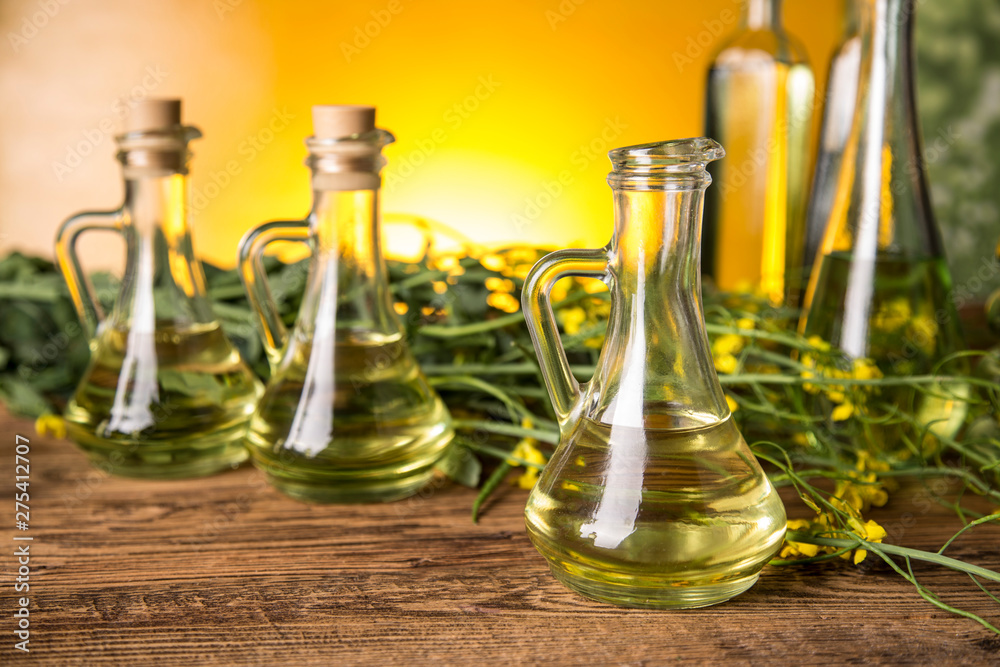 Rapeseed flowers and rapeseed oil in a bottle on the table Rapeseed flowers and rapeseed oil in a bottle on the table