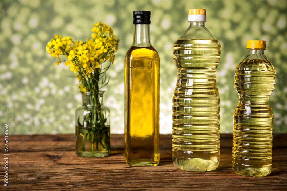 Rapeseed flowers and rapeseed oil in a bottle on the table