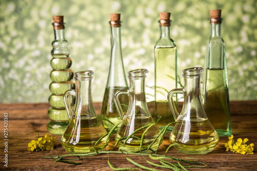 Foto Seeds and rape flowers in bottles and carafes with rapeseed oil