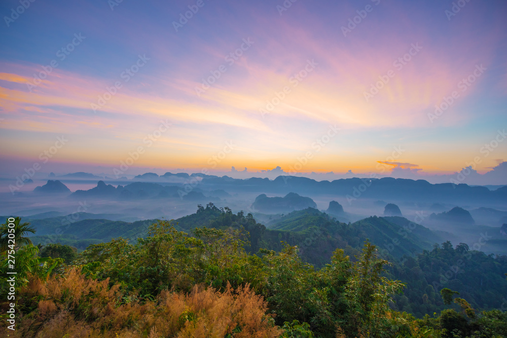 Beautiful mountain range with sky blue and orange light of the sun through the clouds in the sky, Background sky during Sunrise with fog on mountain, Abundant lush forest-Image