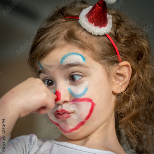 Isolated five year old girl close up portrait dressed up as clown with make up