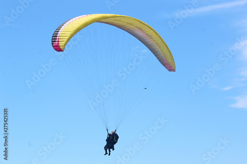 Tandem paraglider flying yellow wing