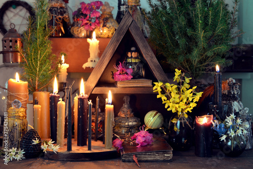 Burning candles, flowers and crystal gem stones on witch table.