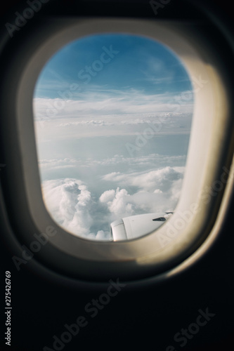 Airplane window with clouds and sky in the evening