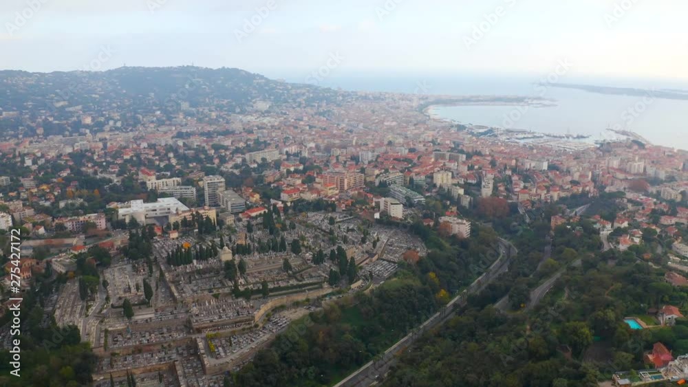 Aerial, tilt up, drone shot, over La Croix des gardes and Cimetiere du grand jas graveyard. overlooking the marina and the mediterranean ocean, on a cloudy day, in Cannes, French Riviera, in France Aerial, tilt up, drone shot, over La Croix des gardes and Cimetiere du grand jas graveyard. overlooking the marina and the mediterranean ocean, on a cloudy day, in Cannes, French Riviera, in France