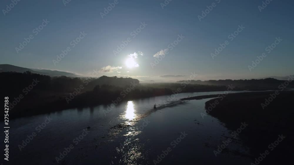 Flying over river with trees and sun in the background Flying over river with trees and sun in the background