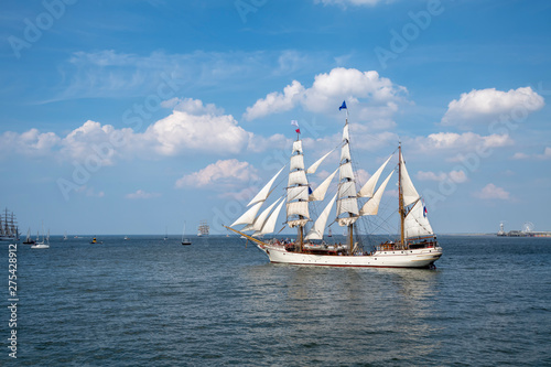 Antique tall ship, vessel leaving the harbor of The Hague, Scheveningen under a sunny and blue sky.