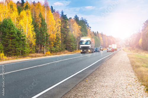 Trucks and cars go on the road in the autumn