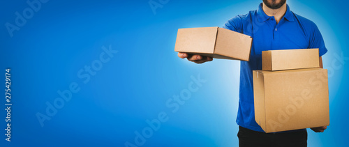 delivery service man holding cardboard boxes on blue background copy space photo