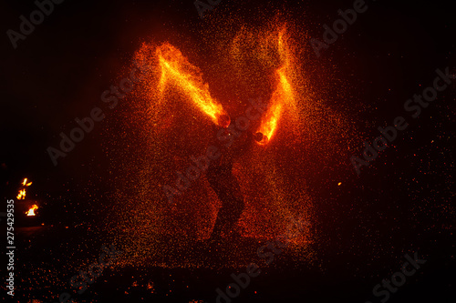 Fire show, dancing with flame, male master juggling with fireworks, performance outdoors, draws a fiery figure in the dark, bright sparks in the night. A man in a suit LED dances with fire.