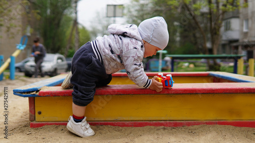 Adorable toddler in the white hat outdoor on the playground