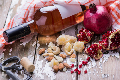 Rose wine bottle with red natural pomegranate and cheese on awooden table.