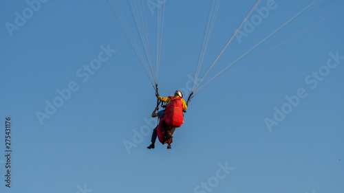 Paraglider with passanger flying in the blue sky.