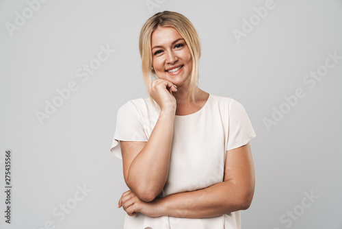 Smiling beautiful young amazing blonde woman posing isolated over grey wall background dressed in basic white t-shirt.