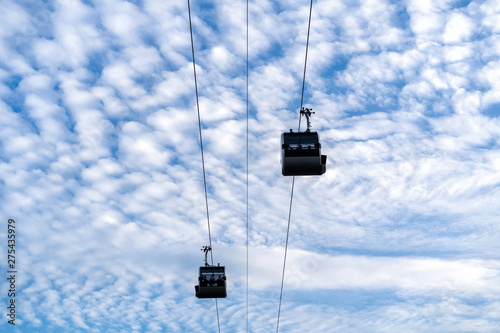 cableway cabins on a background of blue sky and white clouds in sunny summer weather