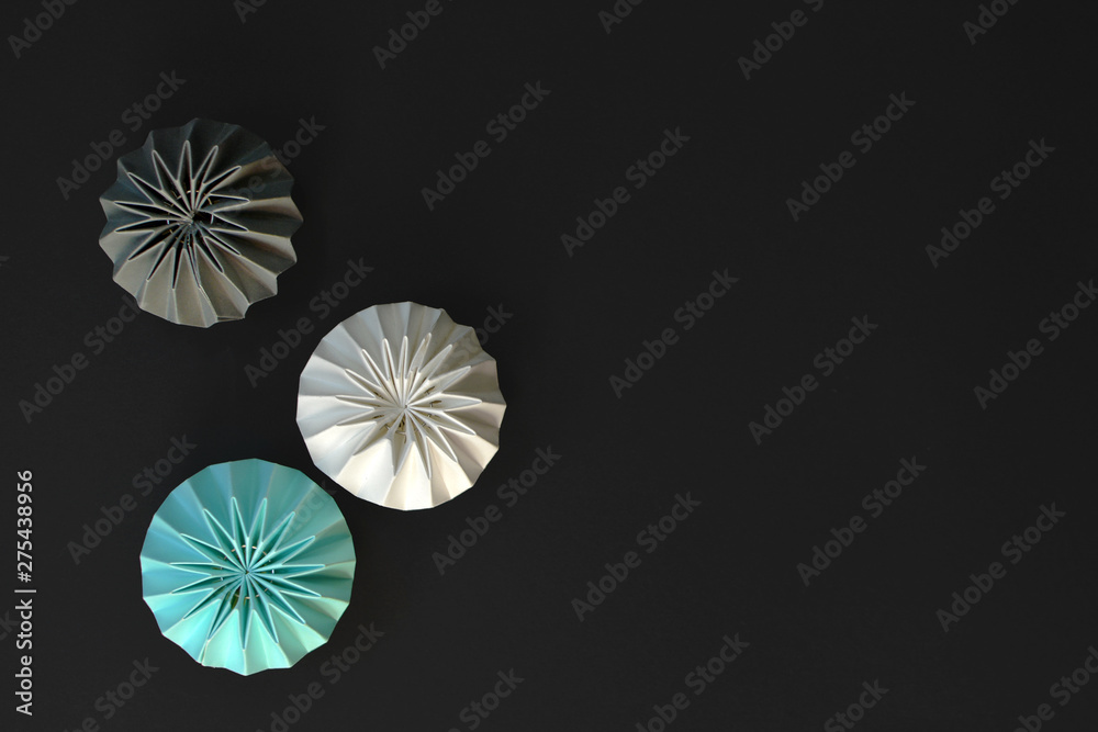 Abstract light teal, gray and white pleated lampions on black background with copy space