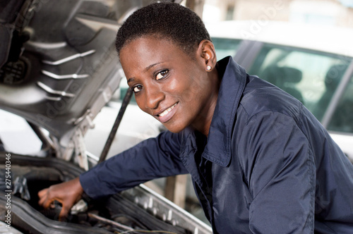 Young female mechanic repairs a car by putting the engine in good condition. photo