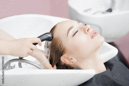 Washing hair of beautiful blonde girl in beauty salon, coloring
