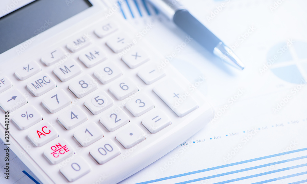 White calculator and report with chart and graph, concept of annual financial profit overview, banking and investment, copy space, macro, close up White calculator and report with chart and graph, concept of annual financial profit overview, banking and investment, copy space, macro, close up
