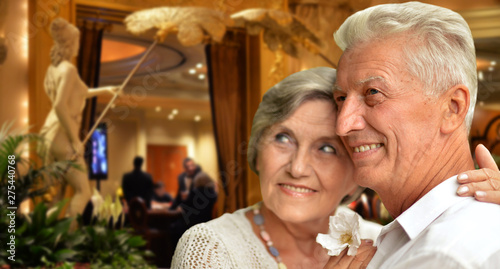 Portrait of happy senior couple hugging against blurred hotel interior background