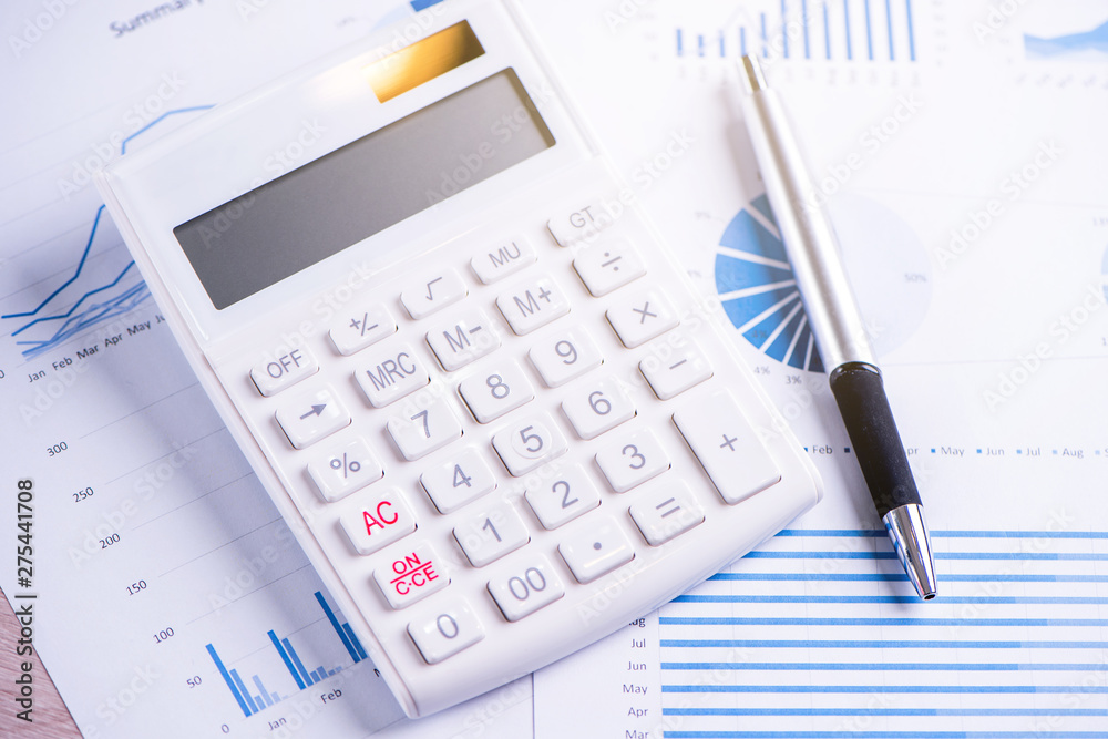 White calculator and report with chart and graph, concept of annual financial profit overview, banking and investment, copy space, macro, close up White calculator and report with chart and graph, concept of annual financial profit overview, banking and investment, copy space, macro, close up