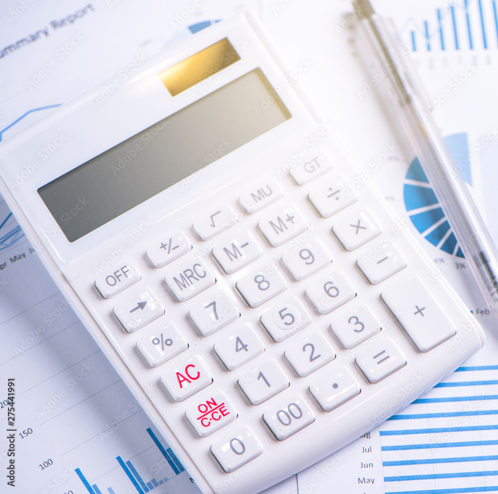 White calculator and report with chart and graph, concept of annual financial profit overview, banking and investment, copy space, macro, close up White calculator and report with chart and graph, concept of annual financial profit overview, banking and investment, copy space, macro, close up