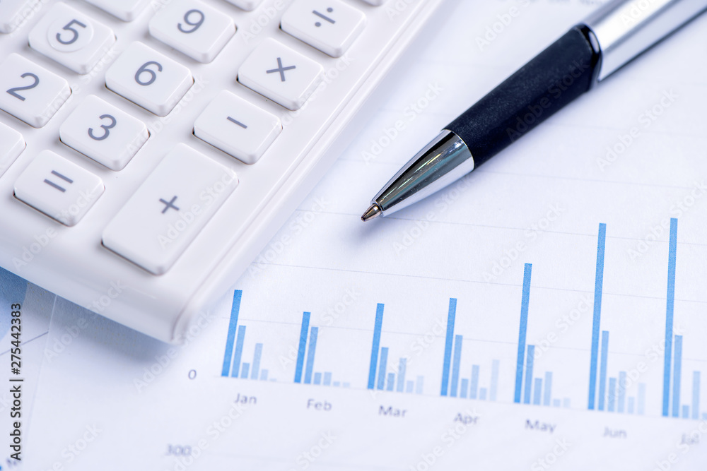 White calculator and report with chart and graph, concept of annual financial profit overview, banking and investment, copy space, macro, close up White calculator and report with chart and graph, concept of annual financial profit overview, banking and investment, copy space, macro, close up