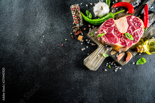 Raw ossobuco meat, beef steak with spices for cooking, black stone concrete background