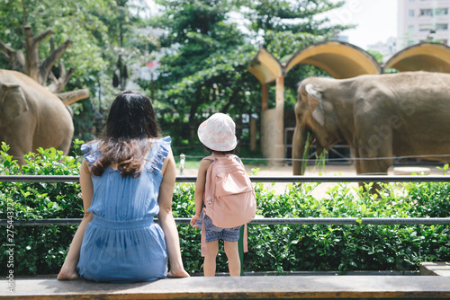 Photography Happy mother and daughter watching and feeding elephants in zoo.