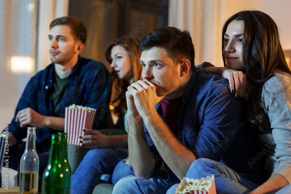 friendship and leisure concept - friends with beer and popcorn watching tv at home at night friendship and leisure concept - friends with beer and popcorn watching tv at home at night