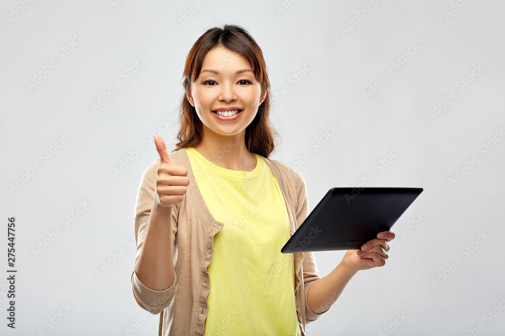 technology and people concept - happy asian woman using tablet computer over grey background technology and people concept - happy asian woman using tablet computer over grey background