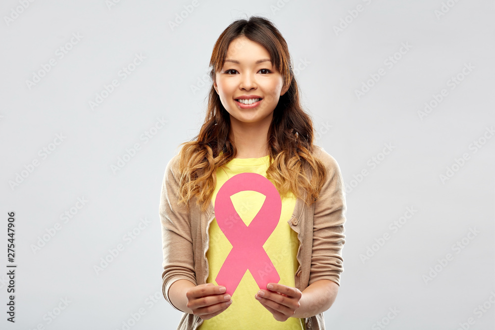 health, charity and people concept - happy asian young woman with pink breast cancer awareness ribbon over grey background health, charity and people concept - happy asian young woman with pink breast cancer awareness ribbon over grey background
