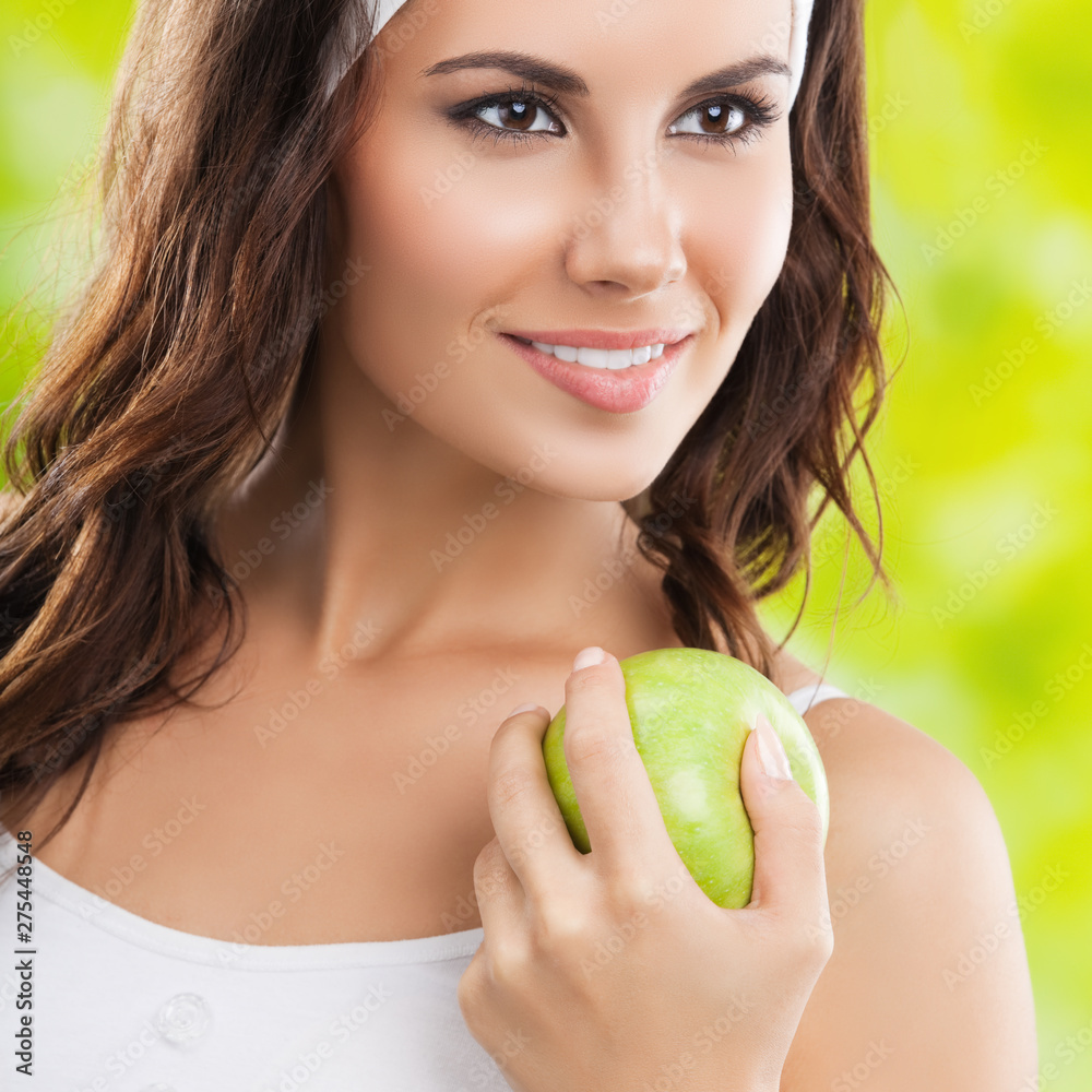 young happy dark haired girl in sportswear with green apple, outdoor young happy dark haired girl in sportswear with green apple, outdoor