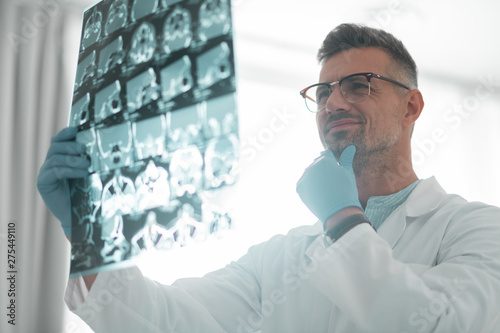 Grey-haired surgeon looking at ultrasound investigation photo